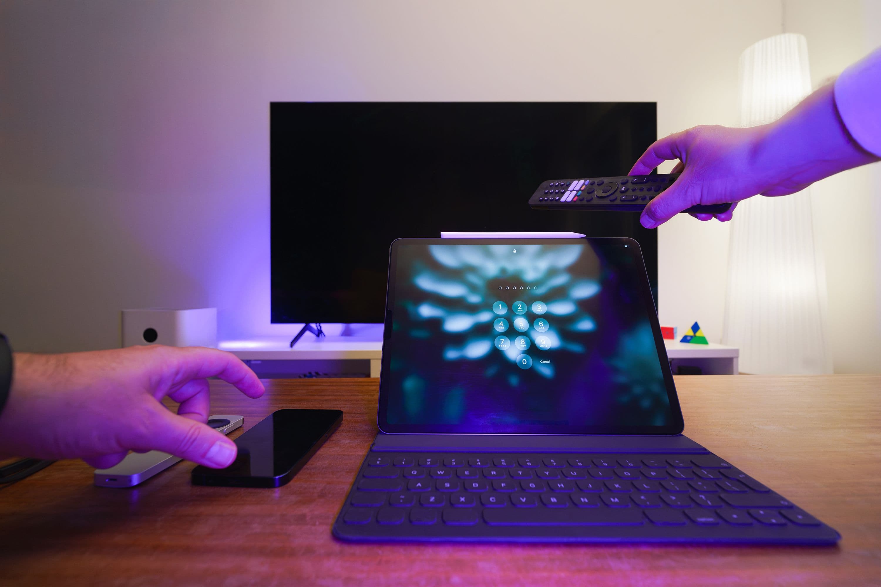 Tablet, phone, and remote in front of a television in a modern streaming setup.