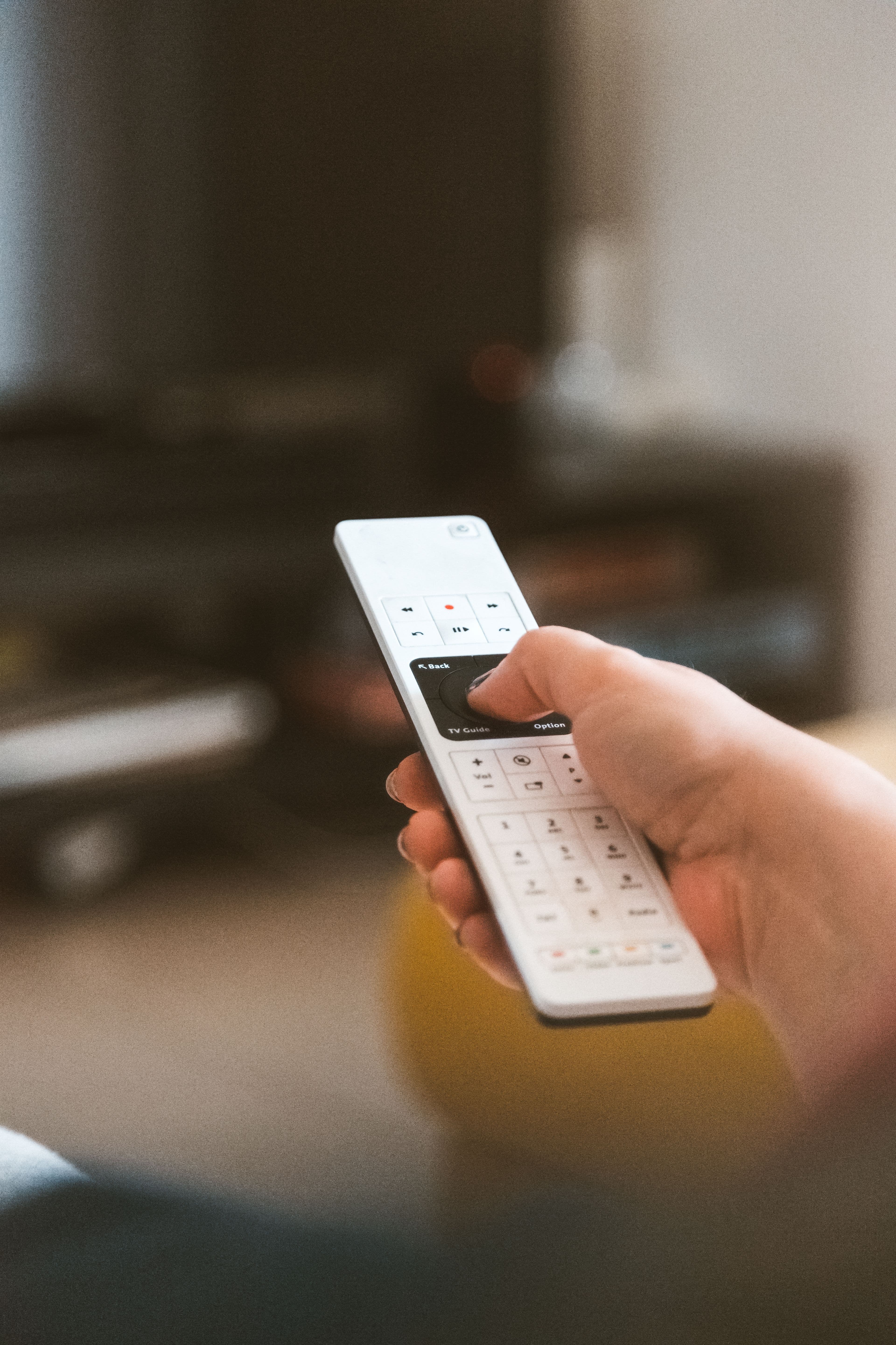 Close-up of a remote control in front of a television.